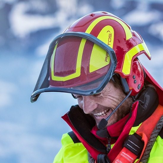 Worker wearing a red and yellow PROTOS helmet with face shield and headset microphone